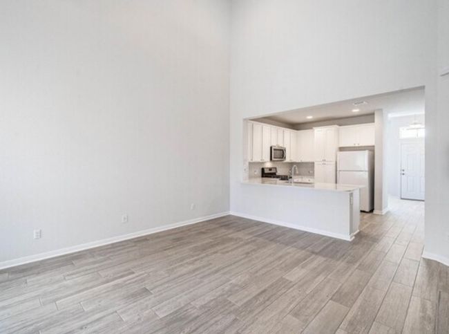 Unfurnished living room featuring a high ceiling and light wood-style flooring | Image 8