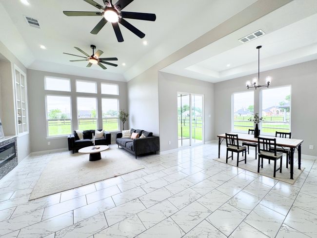 Living room with light marble finish flooring, recessed lighting, a ceiling fan, plenty of natural light, and a raised ceiling | Image 6
