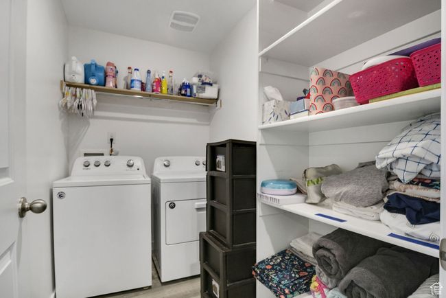 Laundry room with washing machine and dryer and light wood-style flooring | Image 12