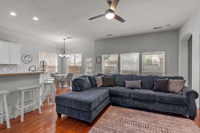 Living room with light wood finished floors, plenty of natural light, recessed lighting, and ceiling fan with notable chandelier | Image 20