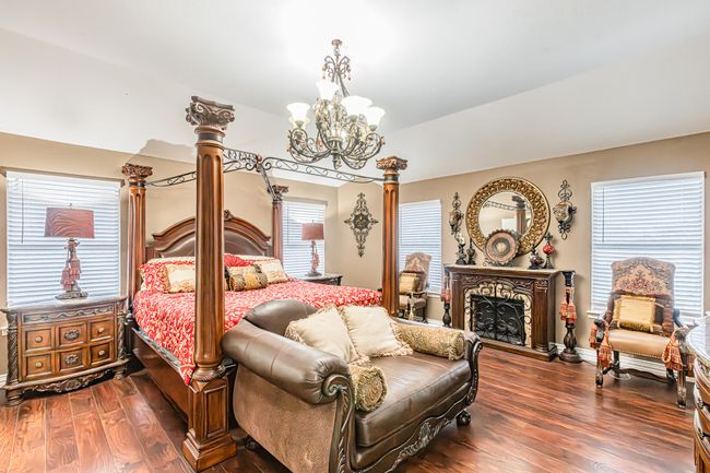 Bedroom with dark wood-type flooring, a chandelier, vaulted ceiling, and a fireplace | Image 19