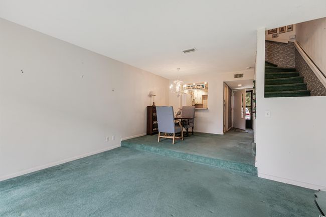 Unfurnished living room with stairs, a notable chandelier, visible vents, and carpet | Image 12