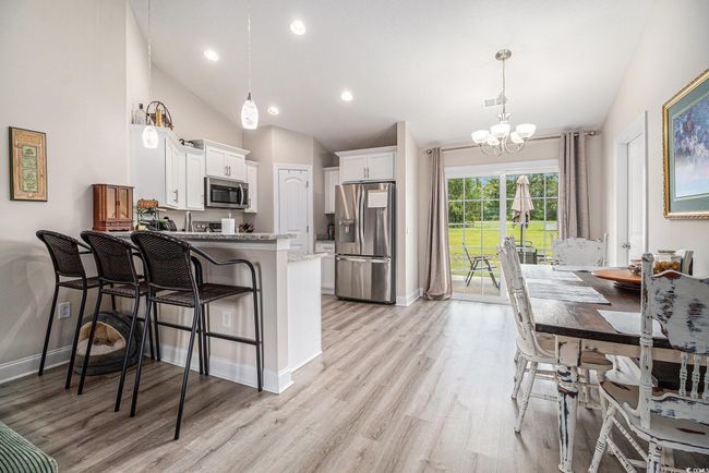Kitchen featuring appliances with stainless steel finishes, lofted ceiling, a chandelier, a peninsula, and white cabinets | Image 9