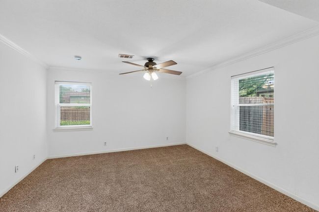 Carpeted spare room with crown molding, healthy amount of natural light, a ceiling fan, and a smoke detector | Image 26