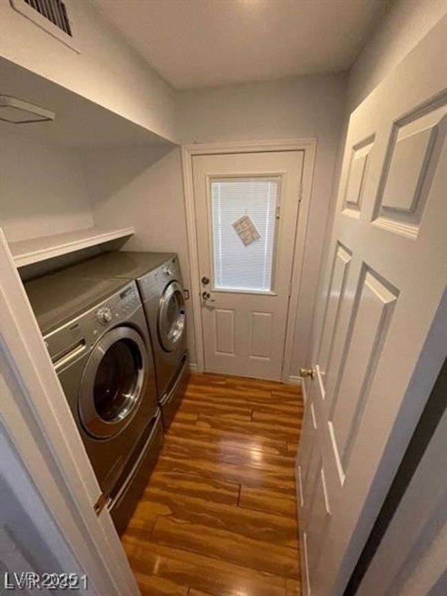 Clothes washing area with dark wood finished floors, visible vents, washing machine and clothes dryer, and laundry area | Image 10