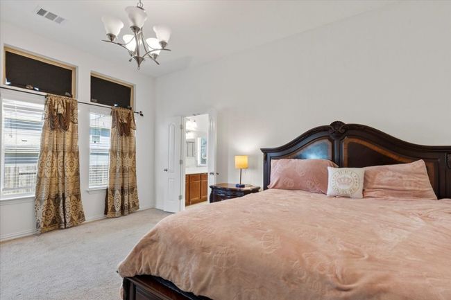 Bedroom with an inviting chandelier, visible vents, light carpet, baseboards, and ensuite bathroom | Image 15