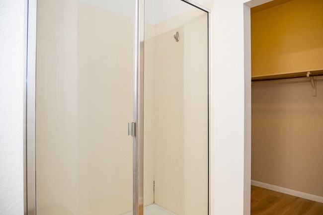 Full bathroom with a stall shower, wood finished floors, baseboards, and a walk in closet | Image 15