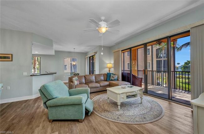 Living room with wood finished floors, a ceiling fan, and a chandelier | Image 9
