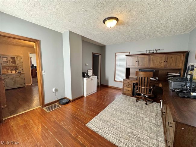 Home office featuring dark wood-style flooring and a textured ceiling | Image 8