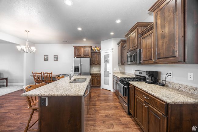 Kitchen with dark wood-type flooring, a kitchen bar, sink, a center island with sink, and appliances with stainless steel finishes | Image 4