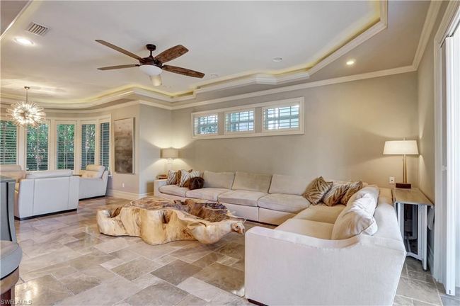 Living room with visible vents, a raised ceiling, ornamental molding, and ceiling fan with notable chandelier | Image 21