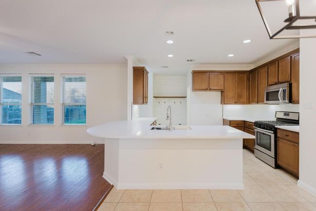 Kitchen with a peninsula, a sink, appliances with stainless steel finishes, crown molding, and backsplash | Image 11