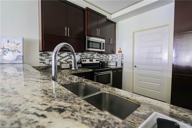 Kitchen featuring stainless steel appliances, light stone counters, and decorative backsplash | Image 6