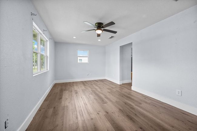 Empty room featuring wood finished floors, a ceiling fan, baseboards, and a textured wall | Image 4