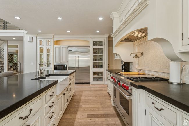 Kitchen featuring built in appliances, dark countertops, backsplash, recessed lighting, and light wood-type flooring | Image 18
