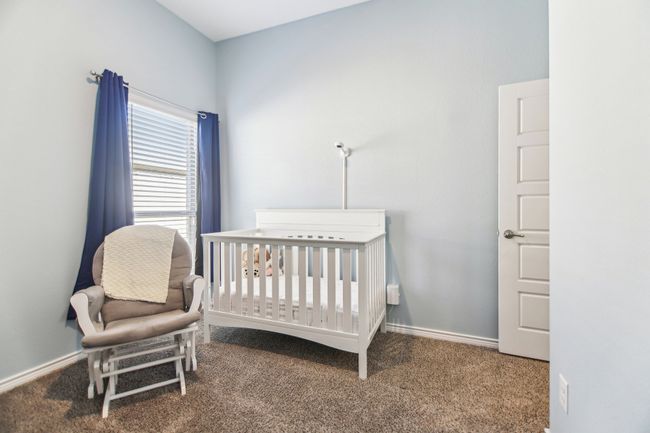 Carpeted bedroom with baseboards and a nursery area | Image 26