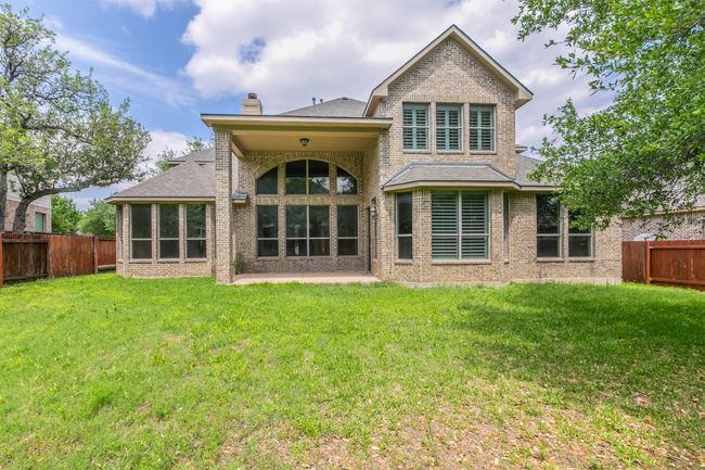 Rear view of property featuring a lawn, a fenced backyard, a chimney, and brick siding | Image 38