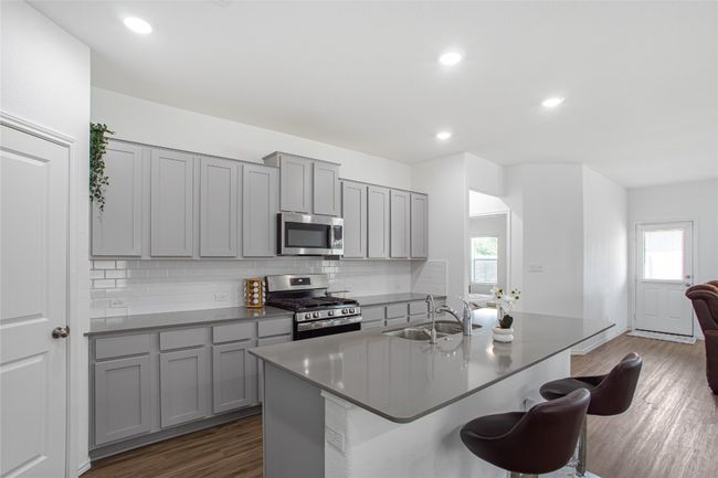 Kitchen with decorative backsplash, gray cabinetry, a sink, and appliances with stainless steel finishes | Image 12