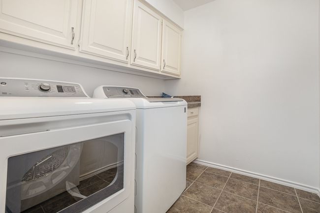 Clothes washing area with independent washer and dryer, baseboards, and cabinet space | Image 17