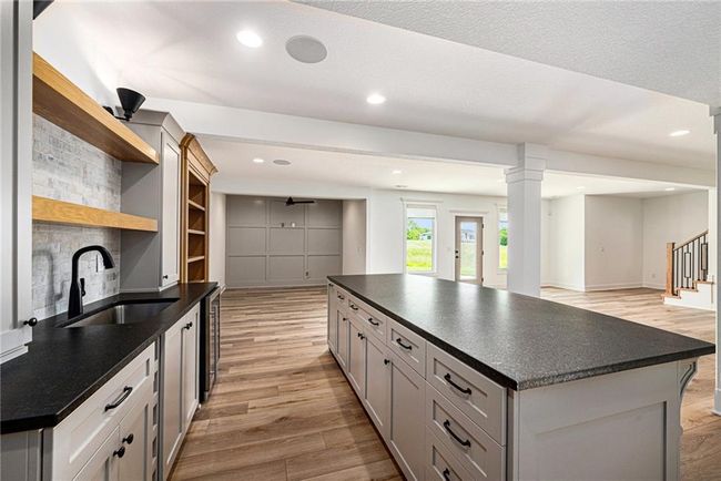 Kitchen with open shelves, a sink, dark countertops, light wood finished floors, and open floor plan | Image 58