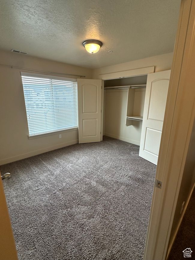 Unfurnished bedroom with a closet, visible vents, carpet flooring, a textured ceiling, and baseboards | Image 12