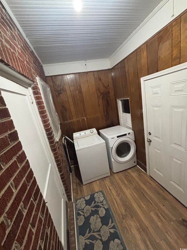 Clothes washing area with independent washer and dryer, wood finished floors, and wood walls | Image 11