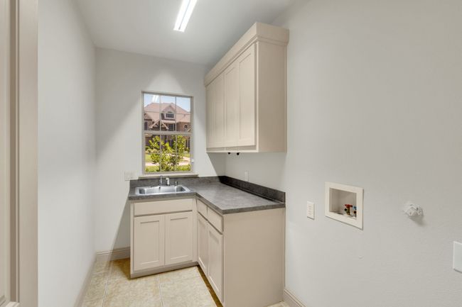 Laundry area with hookup for a washing machine, cabinet space, and light tile patterned floors | Image 30