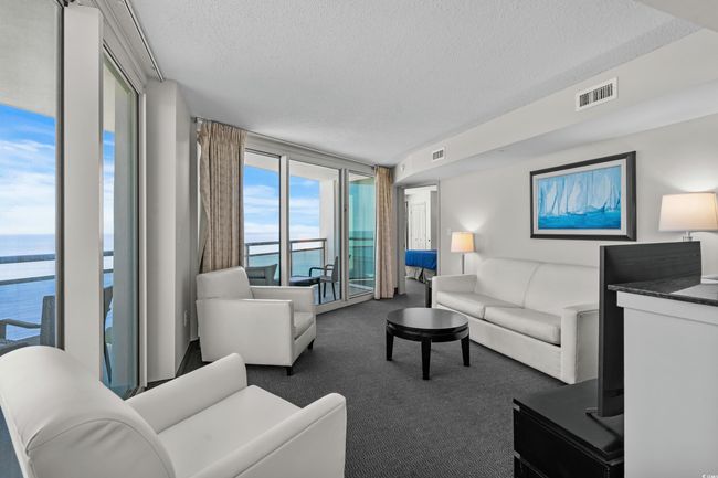 Carpeted living room featuring a textured ceiling, floor to ceiling windows, visible vents, and a water view | Image 4