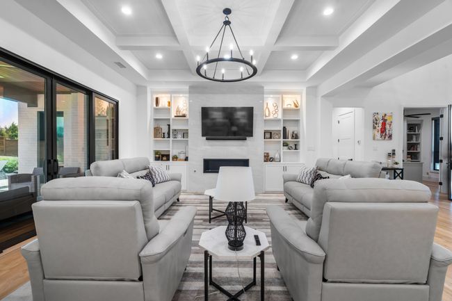 Living room featuring wood finished floors, a chandelier, built in features, coffered ceiling, and beamed ceiling | Image 8