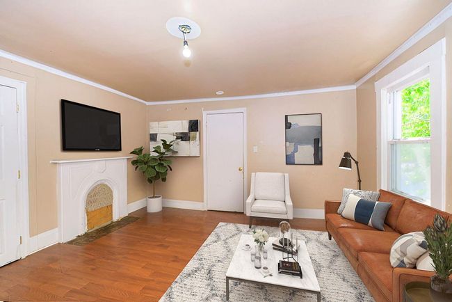 Living room featuring wood finished floors, ornamental molding, and a fireplace with flush hearth | Image 5