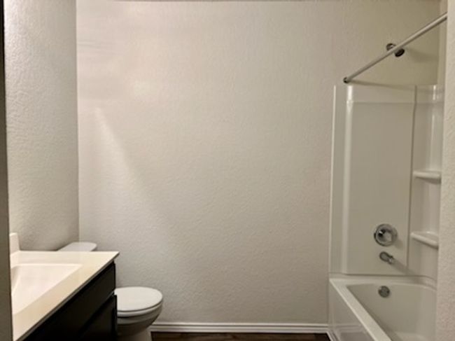 Full bathroom featuring vanity, wood finished floors, shower / bathtub combination, and a textured wall | Image 17