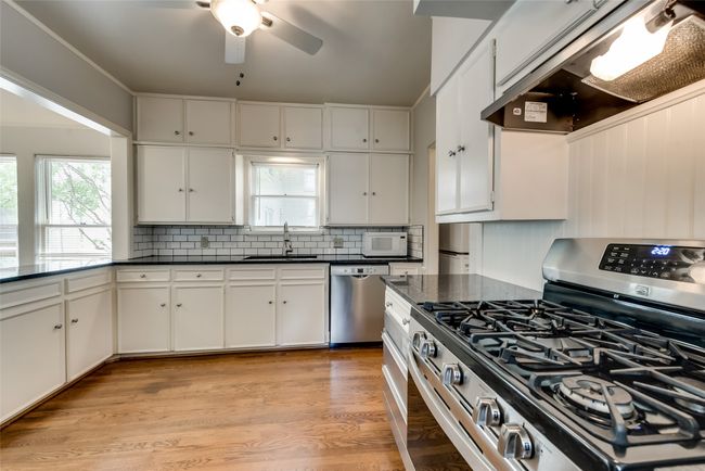 Kitchen with appliances with stainless steel finishes, dark countertops, ventilation hood, and decorative backsplash | Image 14
