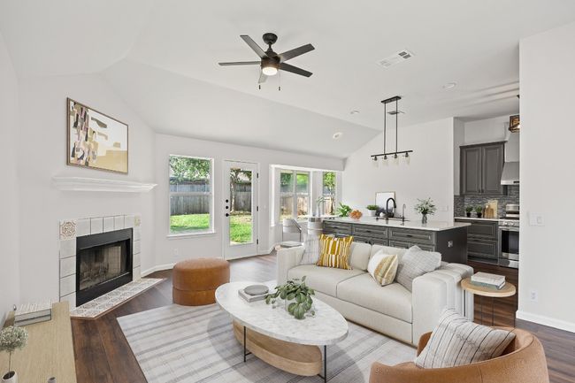 Living room with lofted ceiling, wood finished floors, a ceiling fan, and a tile fireplace | Image 22