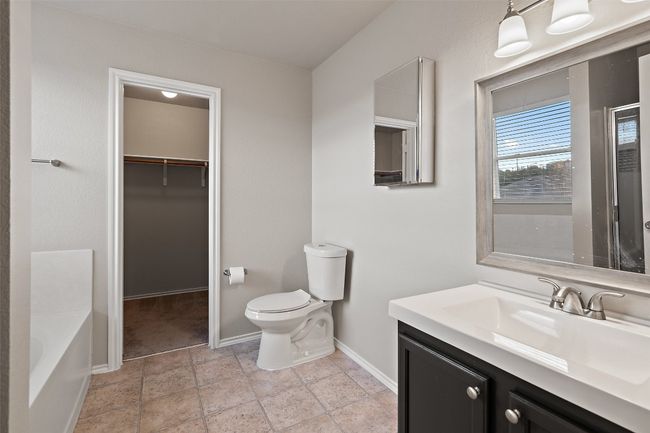 Full bath with vanity, a walk in closet, a tub to relax in, and stone finish floors | Image 20