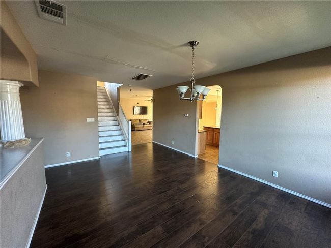 Unfurnished living room featuring dark wood finished floors, stairs, a chandelier, and arched walkways | Image 5