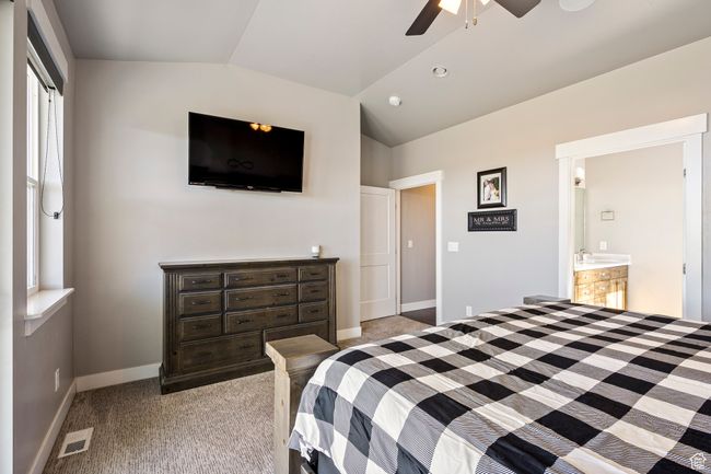 Bedroom featuring baseboards, visible vents, light colored carpet, and vaulted ceiling | Image 24