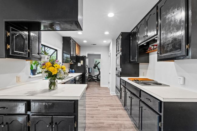 Kitchen featuring black appliances, dark cabinetry, light wood finished floors, light countertops, and recessed lighting | Image 9