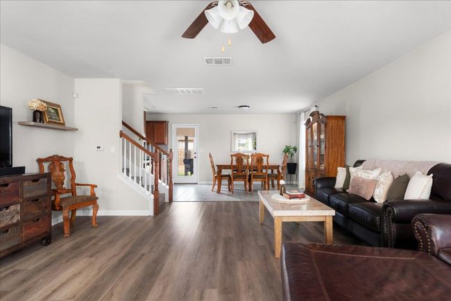 Living room featuring ceiling fan, stairway, wood finished floors, and baseboards | Image 4