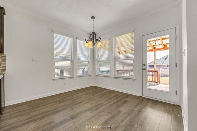 Unfurnished dining area with dark hardwood / wood-style flooring, crown molding, and an inviting chandelier | Image 12