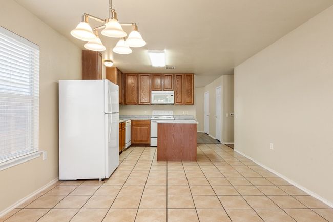 Kitchen featuring white appliances, light countertops, a center island, and plenty of natural light | Image 8