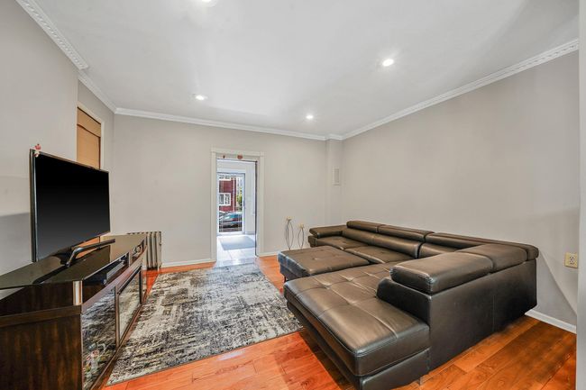 Living room with wood finished floors, recessed lighting, crown molding, and baseboards | Image 8