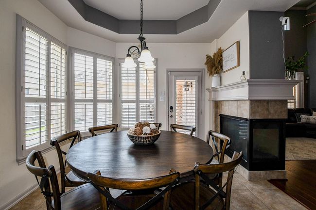 Lovely breakfast area apointed with coffered ceiling and double sided fireplace adjacent to the family room | Image 16