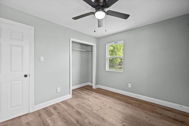 Unfurnished bedroom featuring wood finished floors, baseboards, a closet, and a ceiling fan | Image 12