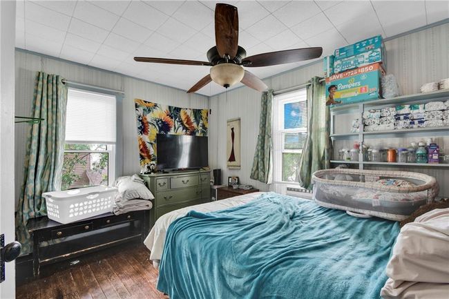 Bedroom with wood-type flooring, ceiling fan, wallpapered walls, and crown molding | Image 13