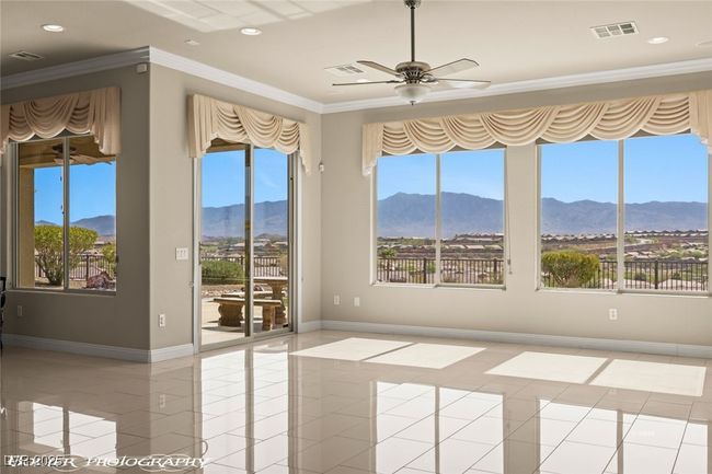 Empty room featuring a mountain view, visible vents, plenty of natural light, ornamental molding, and ceiling fan | Image 32