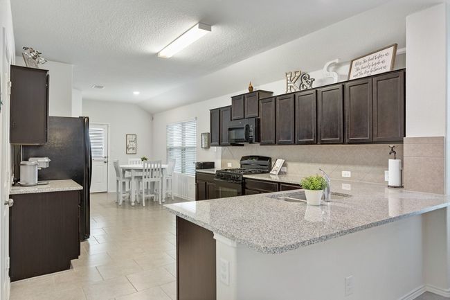 The kitchen offers a breakfast bar perfect for stools, granite countertops, lots of cabinet and work space, and a great dining area! | Image 6