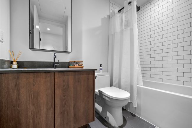 Full bathroom featuring shower / bath combo with shower curtain, vanity, and tile patterned floors | Image 11