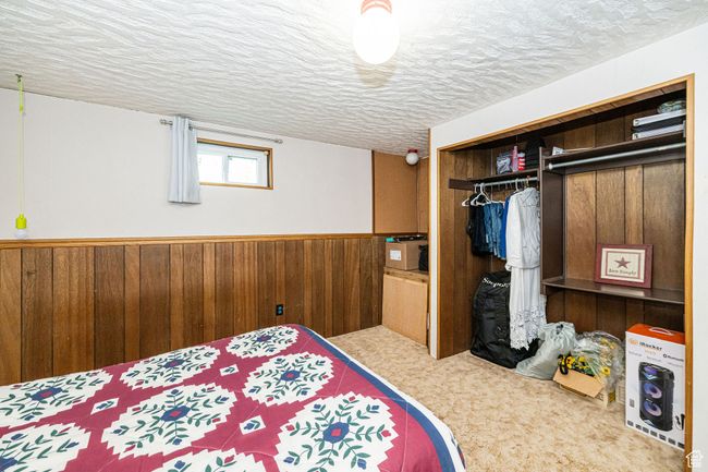 Bedroom featuring a textured ceiling, wainscoting, carpet floors, a closet, and wooden walls | Image 37