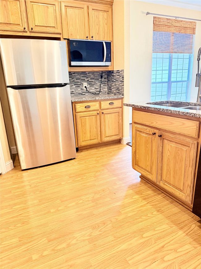 Kitchen featuring appliances with stainless steel finishes, light wood-style flooring, backsplash, and light stone countertops | Image 14