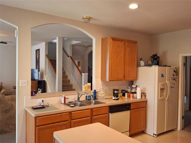 Kitchen featuring light countertops, a sink, white appliances, arched walkways, and decorative backsplash | Image 8